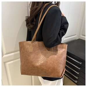 Side view of a vintage dark brown tote bag on model shoulder in modern indoor setting
