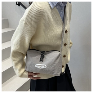 Detail of grey nylon crossbody bag with pleated texture and dual zipper closure