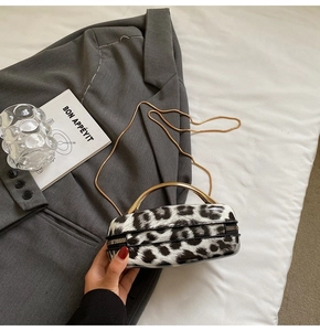 Detail of leopard print oval bag with gold handle and chain on white bedding