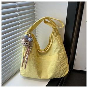 Detail of yellow canvas tote bag with outer pocket and plush charm on a window sill