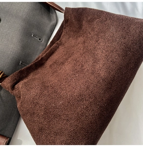 Close-up of deep brown suede texture and stitching on minimalist shoulder bag