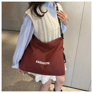 Detail of burgundy large capacity tote bag featuring white FASHION print and woven strap