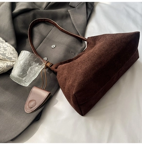 Top view of dark coffee suede shoulder bag with a small pouch on a white surface
