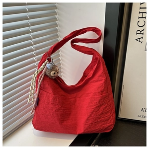 Detail of red crescent nylon hobo bag with textured fabric and plush charm accessory