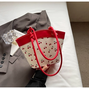 Close-up of woven handle detail and cherry print on red and white mini tote bag