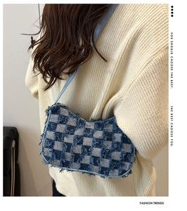 Close-up of blue and white checkered denim crossbody bag with frayed edge detailing
