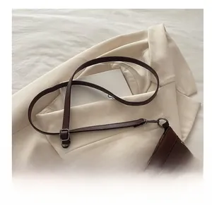Detail of silver rivets and vintage cross charm on a brown suede shoulder tote bag