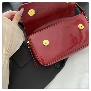 Detail of red patent leather shoulder bag with three golden magnetic snap closures