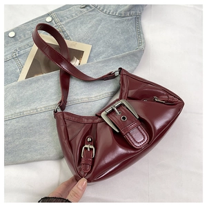 Detail of burgundy patent leather shoulder bag with vintage silver buckle and pleats