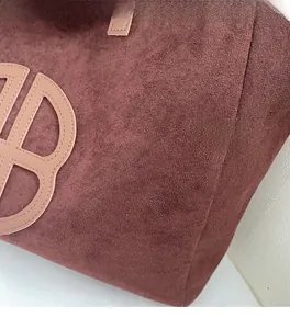 Detail of vintage coffee brown suede tote bag featuring oversized leather logo stitching