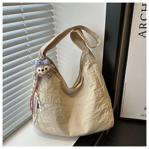 Detail of a large beige canvas tote bag with a soft texture and plush bow charm