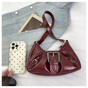 Close-up of burgundy patent leather bag with vintage silver buckle and pleated detail