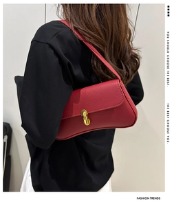 Detail view of red lychee pattern leather shoulder bag with gold capsule clasp on model