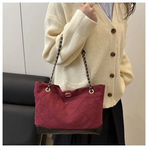 Gros plan du sac matelassé bordeaux avec chaîne dorée et base en cuir noir