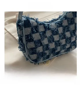 Detailed view of blue and white checkered bag with fringe texture and light blue zipper
