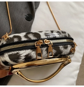 Detailed view of leopard print handbag with gold metal handle and dual zippers