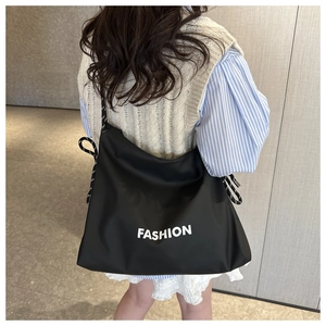 Détail d'un grand sac cabas noir avec imprimé FASHION et cordes tressées sur le côté