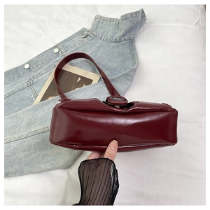 Detail of burgundy glossy PU leather underarm bag with vintage square buckle accent
