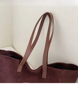 Detail of burgundy suede tote with brown leather straps showing sturdy stitching and texture