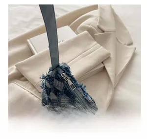 Detail view of smooth metal zipper and frayed denim edges on the star shoulder bag