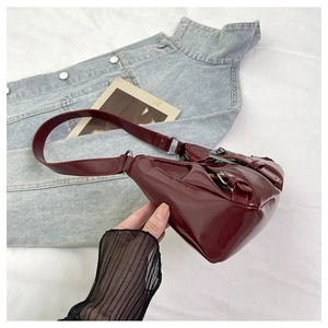 Detail of dark red patent leather shoulder bag with vintage silver metal buckles