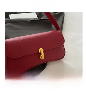 Close-up of red pebble leather shoulder bag with a polished gold oval twist lock closure