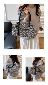 Detail view of a black and white tweed tote bag with faux leather straps and gold buckle accent