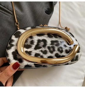 Detail of the leopard print clutch with a gold C-shaped handle and detachable chain strap