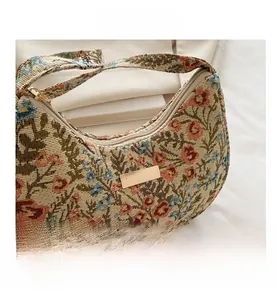 Detail view of vintage beige linen hobo bag with colorful floral embroidery and gold clasp
