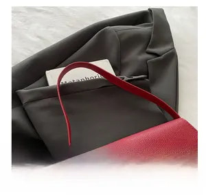 Close-up of a dark red litchi texture leather bag with a golden oval metal twist lock