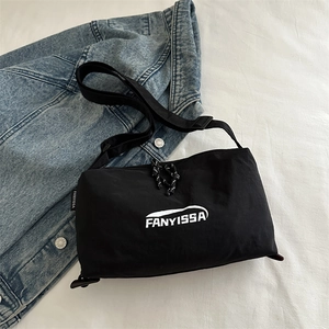 Minimalist black letter print crossbody bag on denim jacket and white linen background
