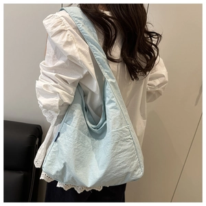 Detail of light blue oversized crescent tote bag showing wrinkled fabric and wide strap