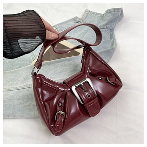 Detail showing the burgundy glossy patent leather with stylish pleats and silver metal buckle