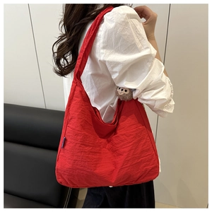 Detail of red canvas crescent bag with a cute monkey keychain and spacious front pocket