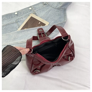 Detail of burgundy ruched shoulder bag showing interior lining and silver buckle hardware