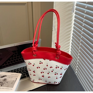 Detailed close-up of a white tote bag with red cherry print and stylish knotted straps