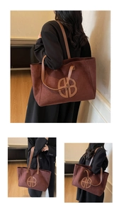Detail of a large brown suede tote bag featuring a circular leather logo and shoulder strap