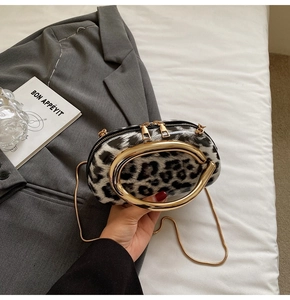 Detail of leopard print evening bag with large gold ring handle and chain strap on bed