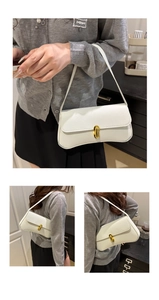 Close-up of white pebble leather baguette bag with elegant golden oval twist lock