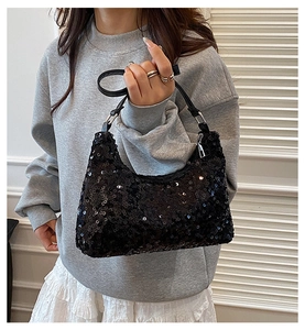 Close-up of black sequined shoulder bag featuring shiny metallic rings and leather handle