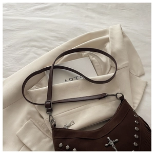 Close-up of brown suede shoulder bag with silver studs, cross emblem and fringe detail