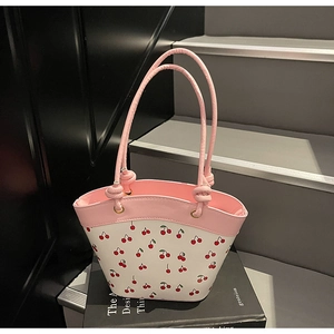 Detailed view of pink and white bucket bag with sweet cherry print and leather handles