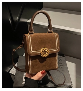 Détail d'un sac en daim marron avec fermoir noeud doré et micro-clous métalliques