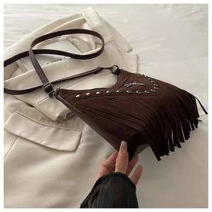 Detail of brown suede shoulder bag featuring silver rivets and long fringe tassels
