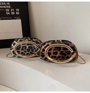 Detail of glossy leopard print crossbody bags with gold C-shaped handles and metal chains