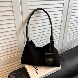 Minimalist black matte shoulder bag with sleek curved handle on a decorative book