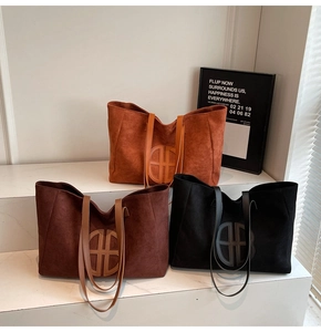 Suede tote bags in orange, brown, and black colors on a minimalist marble display