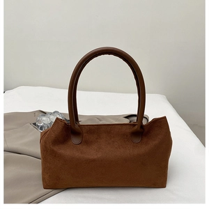 Close-up of deep brown suede tote bag with dual leather handles on a minimal background