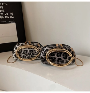 Close-up of leopard print handbag with bold golden horseshoe handle and dual metal zippers