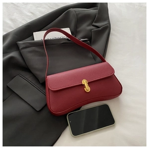 Detail of burgundy litchi leather bag with a stylish golden U-shaped metal lock